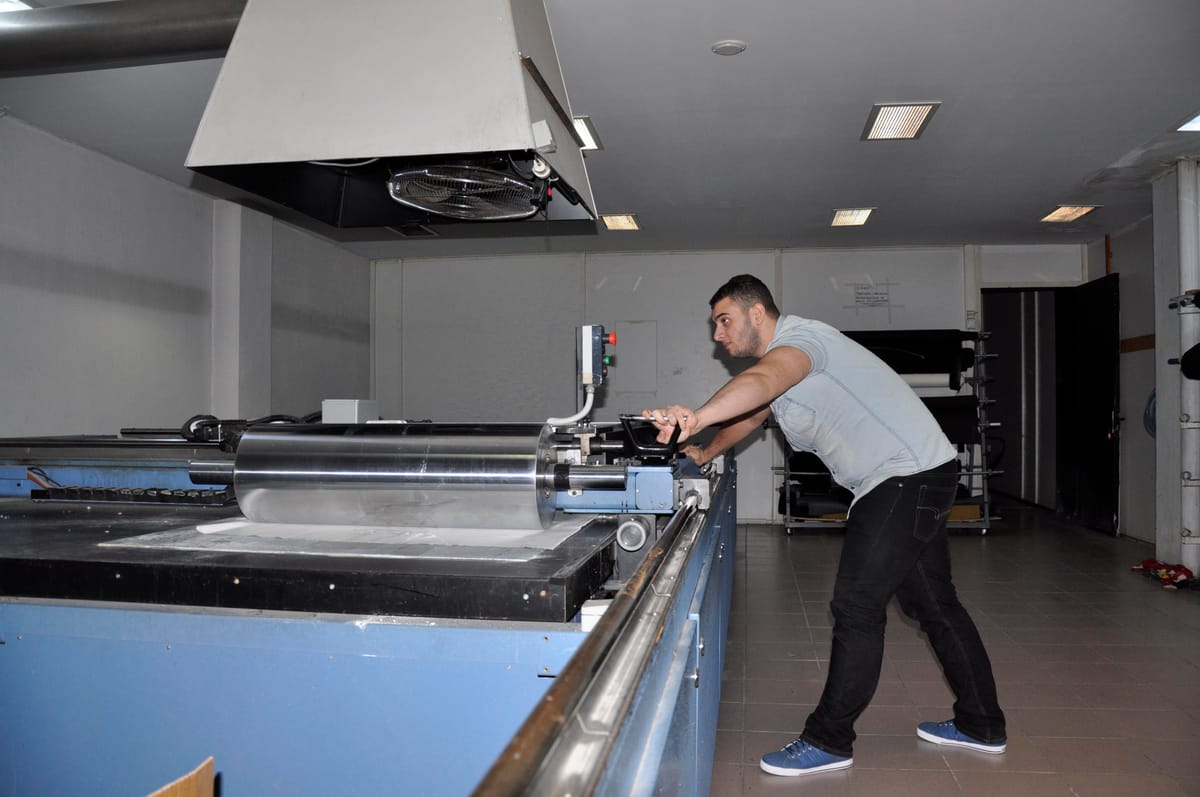 Geniş çalışma masasında desen üzerinde çalışan teknisyen